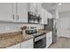 Close-up of kitchen featuring white cabinets, stainless steel appliances, and granite countertops at 1556 E Vesper Trl, Queen Creek, AZ 85140
