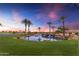 Picturesque pond with tranquil waterfall feature, lush green grass and swaying palms at sunset at 1556 E Vesper Trl, Queen Creek, AZ 85140