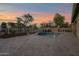 Expansive backyard featuring a sparkling pool, travertine patio, mature trees, and string lights at 1694 E Mia Ln, Gilbert, AZ 85298