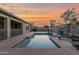 Backyard pool with travertine decking, lounge chairs, string lights, and privacy landscaping at 1694 E Mia Ln, Gilbert, AZ 85298