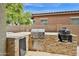 Well-equipped outdoor kitchen with built-in BBQ grill, stainless steel appliances, and stone accents at 1694 E Mia Ln, Gilbert, AZ 85298
