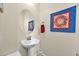 Bright powder room featuring a pedestal sink, decorative mirror and wall art at 1694 E Mia Ln, Gilbert, AZ 85298