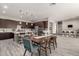 An open dining space, featuring dark wood cabinets, pendant lighting, and light wood-look flooring, flows to the kitchen at 22434 S 226Th Pl, Queen Creek, AZ 85142