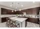 A stunning kitchen features dark wood cabinets, an island with seating and pendant lighting above a white countertop at 22434 S 226Th Pl, Queen Creek, AZ 85142