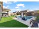 Relaxing backyard featuring a swimming pool, lounge chairs, artificial grass, and a covered patio at 22473 E Twilight Dr, Queen Creek, AZ 85142