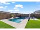 A cozy backyard featuring a pool, artificial grass, lounge chairs, and privacy fencing creating a private retreat at 22473 E Twilight Dr, Queen Creek, AZ 85142