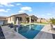 Beautiful backyard with a pool, artificial grass, lounge chairs, and covered patio, perfect for outdoor entertaining at 22473 E Twilight Dr, Queen Creek, AZ 85142