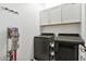 A laundry room with overhead cabinets, washer, dryer, and a Dyson vacuum cleaner on the wall at 22473 E Twilight Dr, Queen Creek, AZ 85142