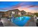 Backyard view showcasing a sparkling pool with lounge chairs, artificial turf, and a covered patio at 22473 E Twilight Dr, Queen Creek, AZ 85142
