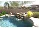 Sparkling pool with a rock waterfall feature and mature landscaping, offering a serene retreat at 25929 N 84Th Ln, Peoria, AZ 85383