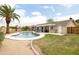 Backyard featuring a pool, palm tree, covered patio with furniture, and lush green landscaping at 2710 E Cinnabar Ave, Phoenix, AZ 85028