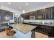 Modern kitchen featuring a granite island, dark wood cabinets, stainless appliances, and pantry at 3028 W T Ryan Ln, Phoenix, AZ 85041