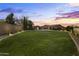 A sprawling backyard showcases a pool with a water slide, and lush lawn as the evening approaches with dramatic clouds at 3381 E Azalea Dr, Chandler, AZ 85286