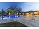 Stunning backyard with a pool, waterfall feature, lush landscaping, and a basketball hoop at dusk at 3381 E Azalea Dr, Chandler, AZ 85286