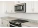 Modern kitchen featuring granite countertops, stainless steel microwave, and white cabinetry at 37458 W San Clemente St, Maricopa, AZ 85138