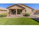 Inviting backyard with a covered patio, desert landscaping, and well manicured artificial turf at 40707 W Pryor Ln, Maricopa, AZ 85138