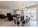 Open-concept dining area with chandelier lighting, view into the living room, and outdoor patio access at 40707 W Pryor Ln, Maricopa, AZ 85138
