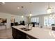 Open kitchen with island and stainless steel sink overlooking living and dining areas at 40707 W Pryor Ln, Maricopa, AZ 85138
