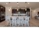 Modern kitchen island with white countertop, bar stool seating, and dark wood cabinetry at 40707 W Pryor Ln, Maricopa, AZ 85138
