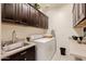 Functional laundry room with dark wood cabinets, sink, and washer-dryer at 40707 W Pryor Ln, Maricopa, AZ 85138