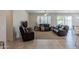 Bright living room featuring tile floors, large windows with shutters, and plush leather furniture at 40707 W Pryor Ln, Maricopa, AZ 85138