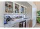 The in-home bar features white marble countertops, glass shelving, a wine refrigerator, and a sink for convenient entertaining at 4617 E Elmwood Cir, Mesa, AZ 85205