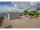Spacious backyard featuring gravel, sheds, and mature trees, creating a private outdoor retreat at 5317 E Baltimore St, Mesa, AZ 85205