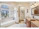 Elegant bathroom featuring stone countertops, soaking tub, large window, and refined finishes for a luxurious experience at 5523 W Creekside Ln, San Tan Valley, AZ 85144