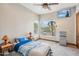 Bright bedroom with a large window showcasing lush greenery, ceiling fan, and a wall mounted TV at 5523 W Creekside Ln, San Tan Valley, AZ 85144
