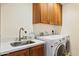 Efficient laundry room features a stainless steel sink, generous wooden cabinetry, and modern washer and dryer units at 6122 E Harvard St, Scottsdale, AZ 85257