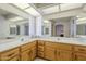 Bathroom featuring dual sinks, wooden cabinets, large mirrors and a skylight for natural lighting at 7925 E Monte Ave, Mesa, AZ 85209
