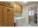 Bright laundry room featuring a washer, dryer and wooden cabinets at 7925 E Monte Ave, Mesa, AZ 85209