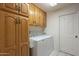 Bright laundry room features abundant wood cabinetry, washer and dryer, and access door at 7925 E Monte Ave, Mesa, AZ 85209