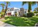 Elegant two-story home with a stone accent, well-manicured lawn, and mature palm trees at 8719 E San Marcos Dr, Scottsdale, AZ 85258
