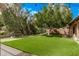 Backyard featuring lush artificial turf, mature trees, and a wrought iron fence at 1777 W Redfield Rd, Gilbert, AZ 85233