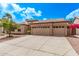 Tan home showcasing desert landscaping, a three-car garage, and a charming tiled roof under a bright blue sky at 1777 W Redfield Rd, Gilbert, AZ 85233