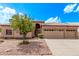 Tan home showcasing desert landscaping, a three-car garage, and a charming tiled roof under a bright blue sky at 1777 W Redfield Rd, Gilbert, AZ 85233