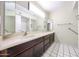 Well-lit bathroom featuring dual sinks, and sleek countertops and a walk-in shower at 4718 W El Caminito Dr, Glendale, AZ 85302