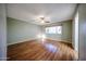 A bright bedroom featuring wood floors, a ceiling fan, and a window for natural light at 4718 W El Caminito Dr, Glendale, AZ 85302