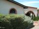 Exterior view showcasing the arched entrance and window detail, complemented by mature desert landscaping at 4718 W El Caminito Dr, Glendale, AZ 85302