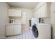 Spacious laundry room featuring modern washer and dryer units and ample cabinet space at 4718 W El Caminito Dr, Glendale, AZ 85302