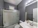 Cozy bathroom includes a shower-tub with sliding doors, a gray color scheme, and a white vanity at 14703 W Hillside St, Goodyear, AZ 85395