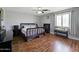 Serene bedroom with hardwood floors, a dark wood bed frame, and ample natural light through shuttered windows at 14703 W Hillside St, Goodyear, AZ 85395