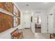 Bright hallway with decorative wall art, bench, and tiled flooring, leading to a bedroom and the front door at 17971 W Meadowbrook Ave, Goodyear, AZ 85395