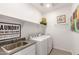 Clean laundry room with sink, modern appliances, shelving, and stylish decor at 17971 W Meadowbrook Ave, Goodyear, AZ 85395
