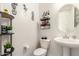 Small, well-decorated half-bathroom featuring decor shelving, circular mirror, and natural lighting at 18134 W Highland Ave, Goodyear, AZ 85395