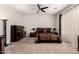 This main bedroom features neutral carpet, ceiling fan, and dark wood furnishings at 18134 W Highland Ave, Goodyear, AZ 85395