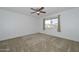 Cozy bedroom with plush carpeting, ceiling fan, and a window offering scenic views at 18610 N Mica Dr, Sun City West, AZ 85375