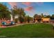 Expansive backyard with lush lawn, covered patio, outdoor seating, and cornhole for entertaining at sunset at 19203 S 185Th Dr, Queen Creek, AZ 85142