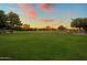 Expansive green space in the community, perfect for outdoor activities and recreation under a beautiful sunset at 19203 S 185Th Dr, Queen Creek, AZ 85142